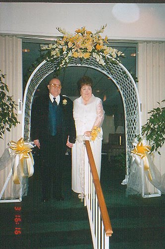 Alfie Geeson and Kathryn Yarrington stand under the wedding arch 